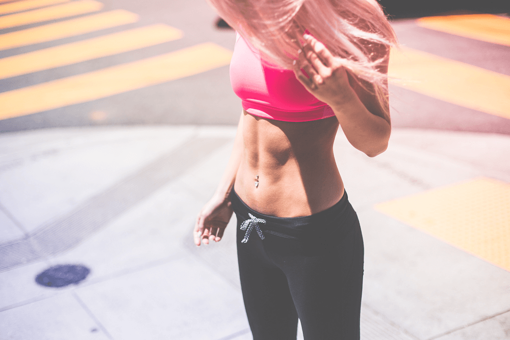 Woman lifting shirt to show 6-pack abs.