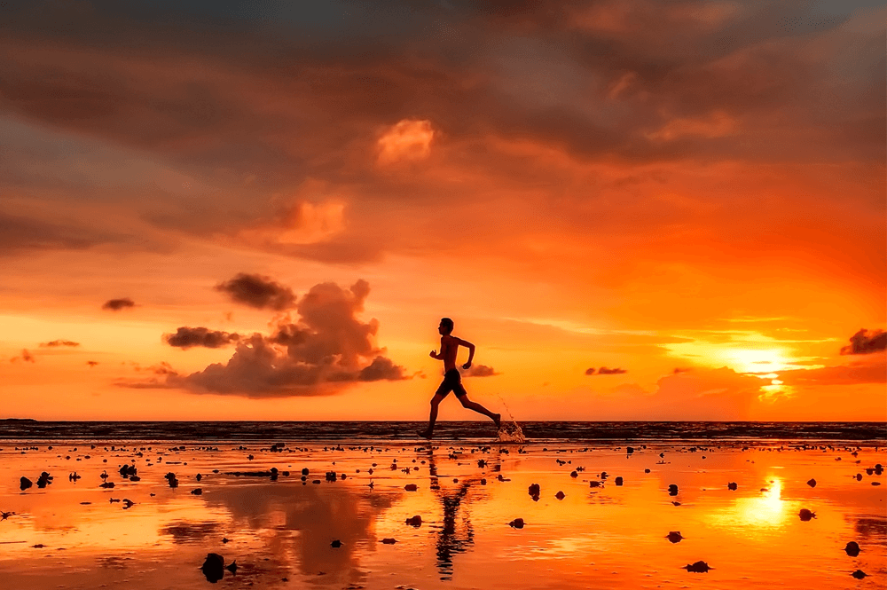 Man running on the beach at sunset.